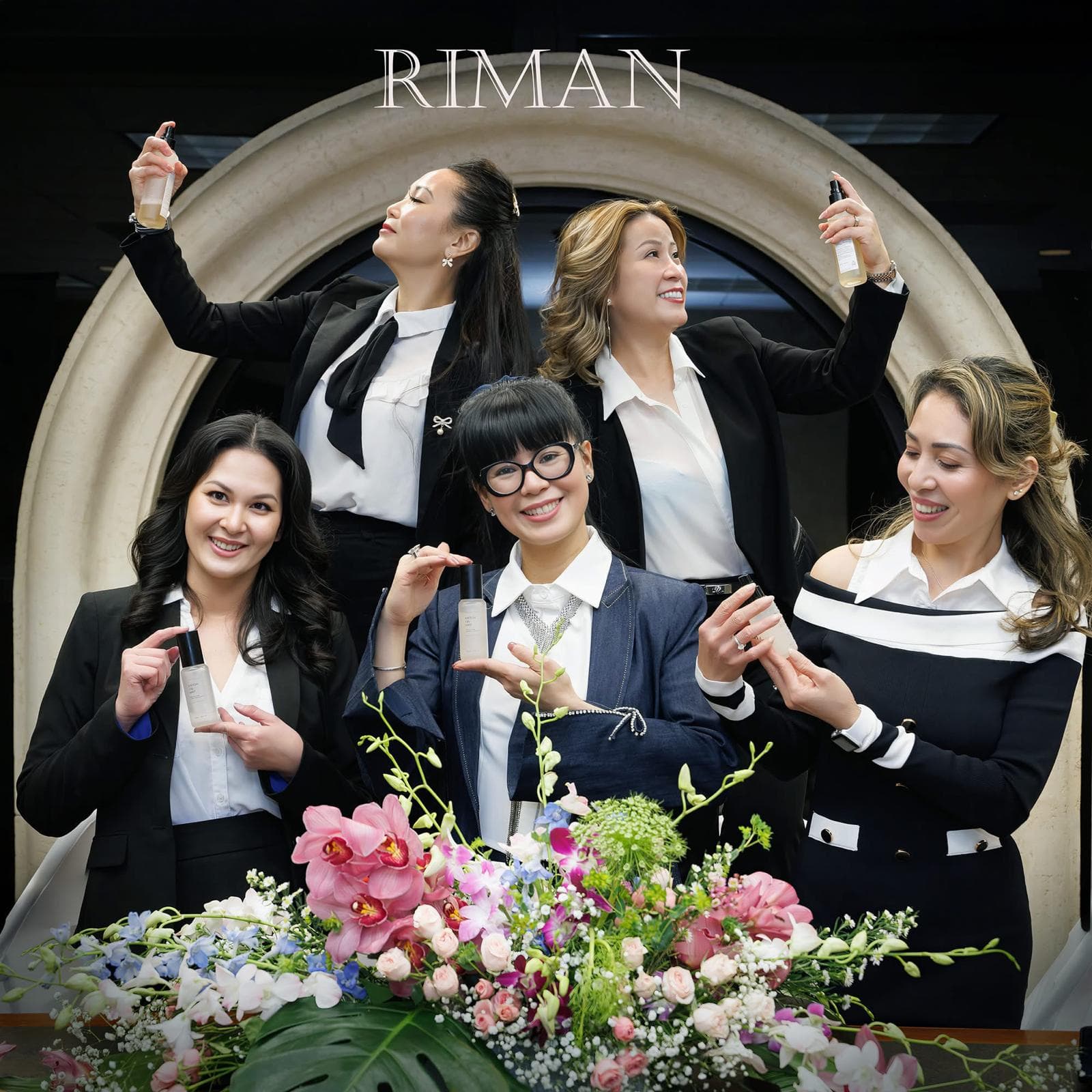 Five women holding skincare products beneath a RIMAN sign, with flowers in the foreground.